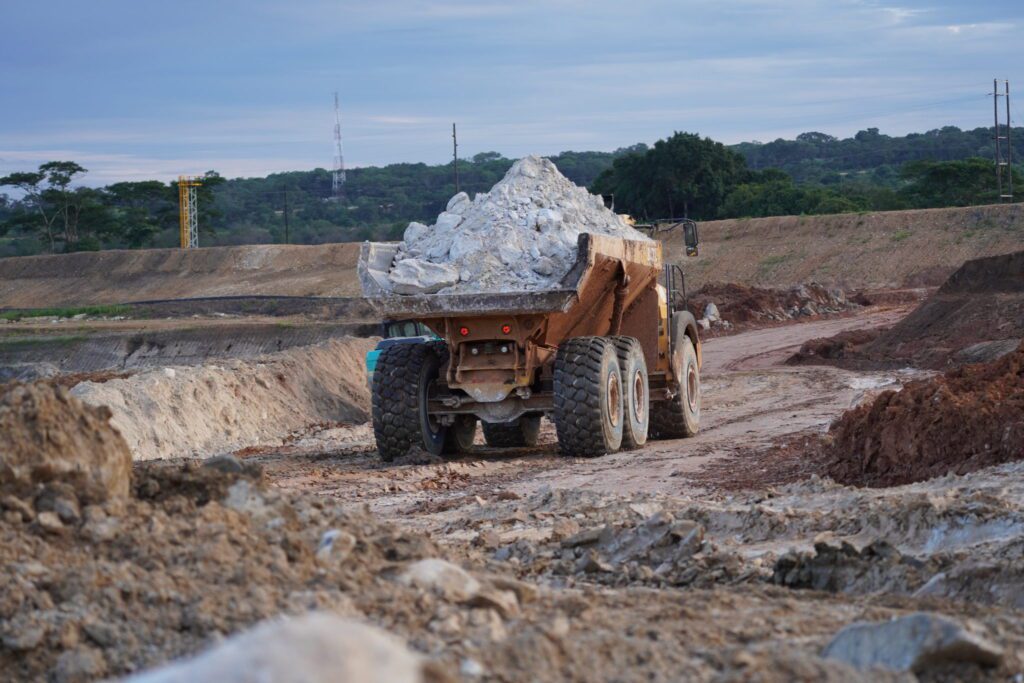 Dump truck carrying rocks on dirt road.