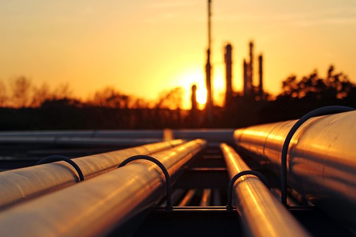 Pipelines at sunset with industrial background.